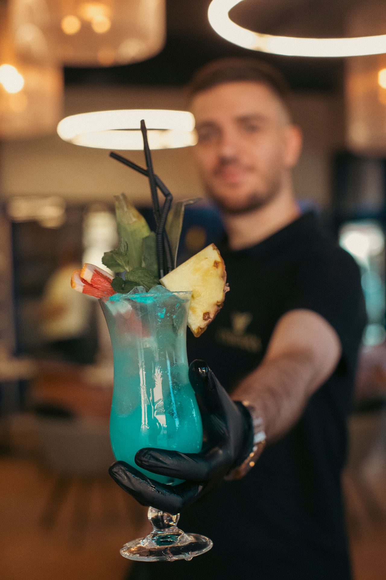 Blue mocktail being served by hand with the lounge softly blurred behind
